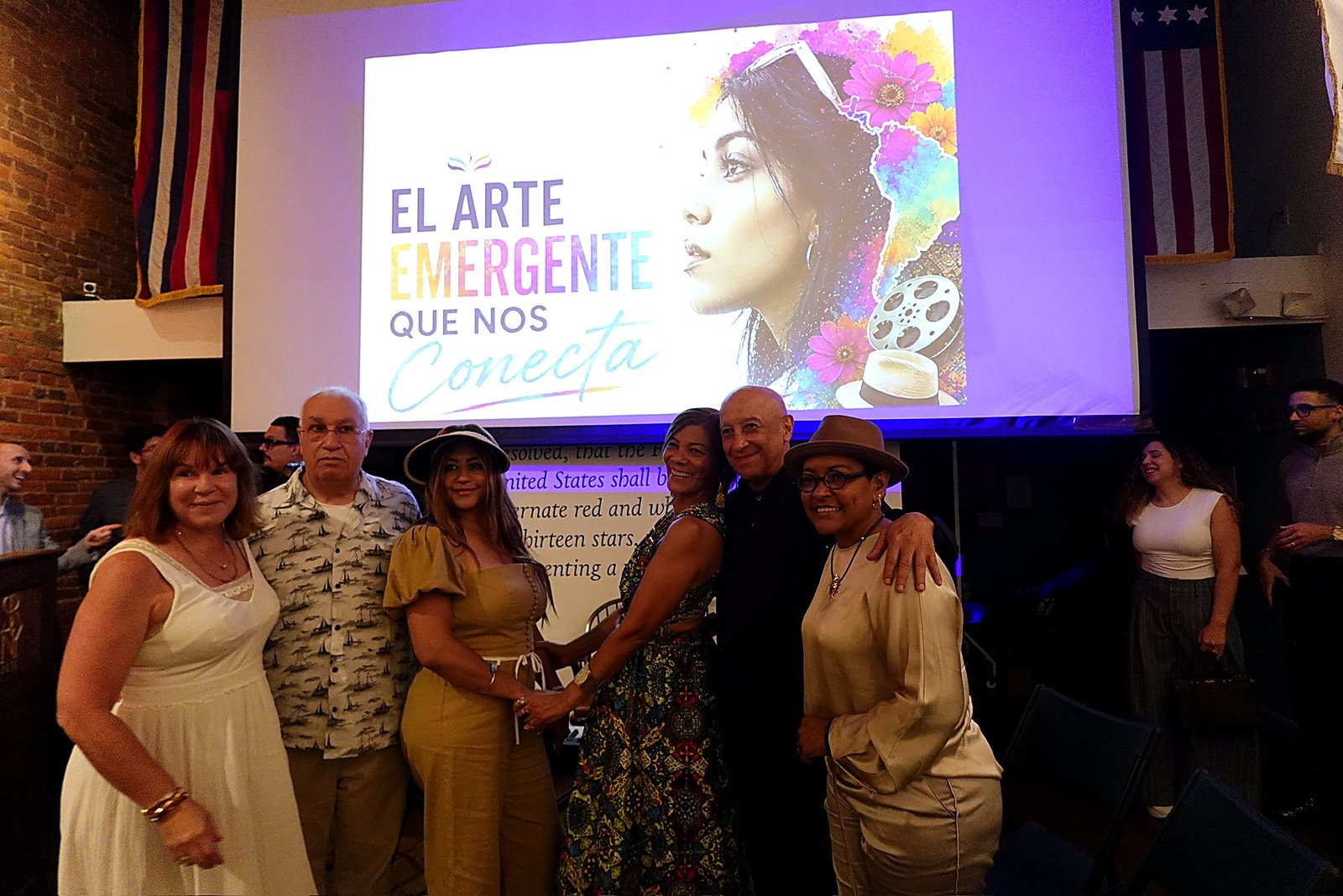 Asistentes invitados posan junto a la pantalla de apertura del evento.